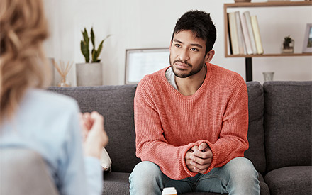 A male client sitting on the sofa listening to his psychologist